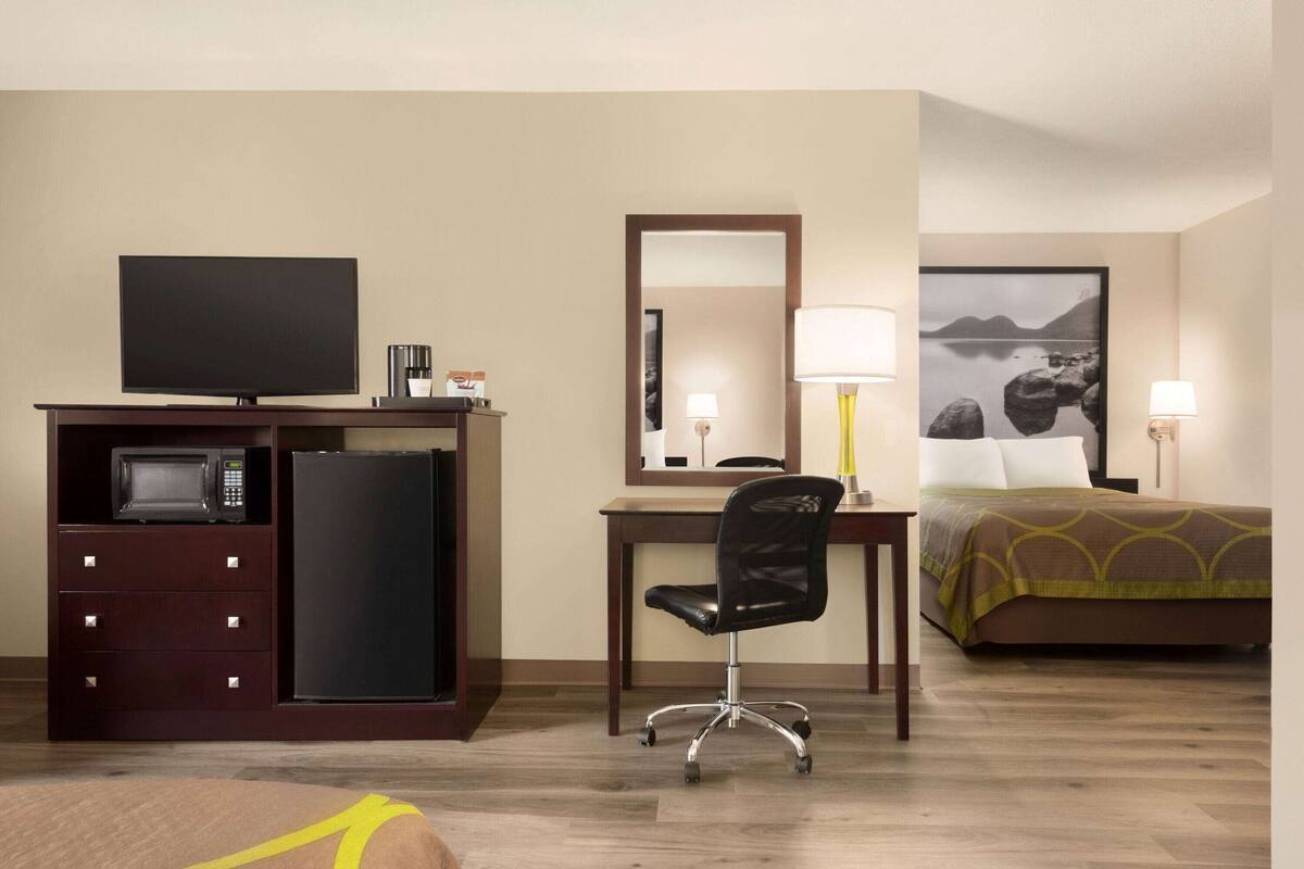 Une chambre d’hôtel équipée d’un lit, d’un bureau avec une chaise, d’une télévision, d’un four à micro-ondes et d’un réfrigérateur.