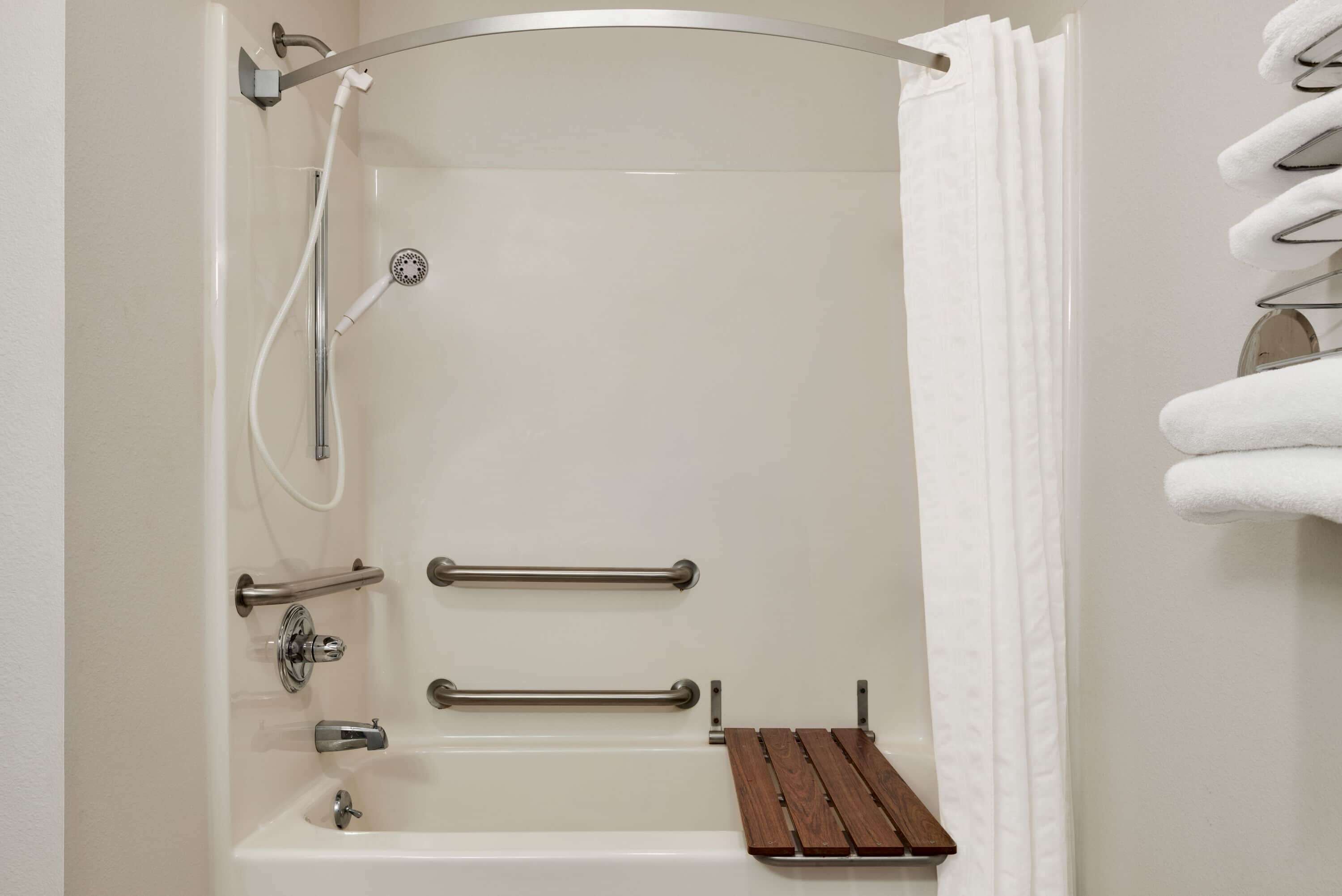 Een moderne badkamer met een bad, douche en handgrepen.