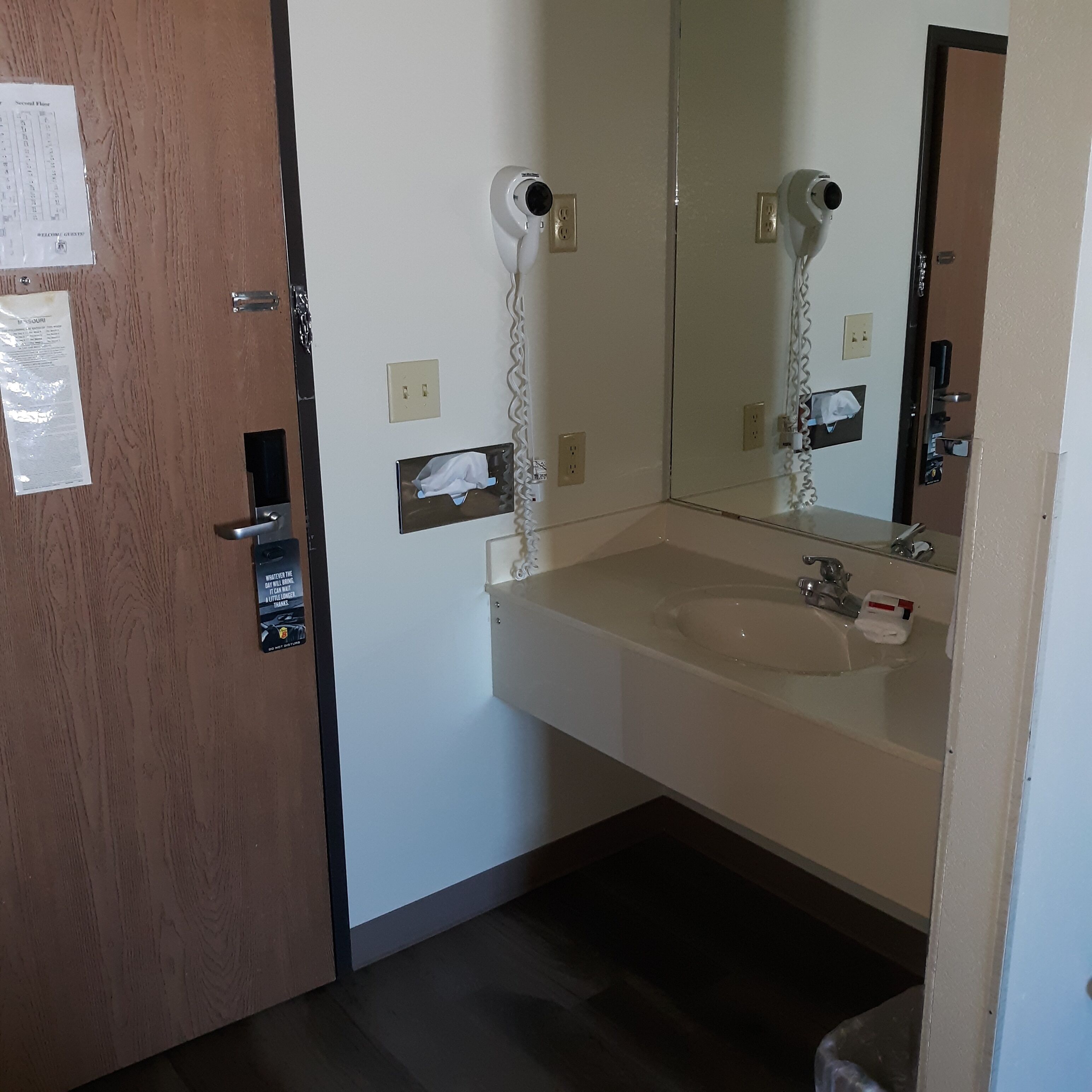 Une salle de bain équipée d’un lavabo, d’un miroir, d’un distributeur de serviettes et d’une porte à clé.