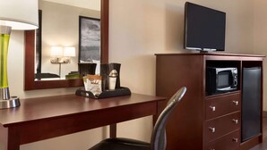 A hotel room with a wooden desk, a flat-screen TV, a microwave, a refrigerator, a chair, a lamp, and a framed picture on the wall. - Super 8 by Wyndham Bethany MO (Bethany)