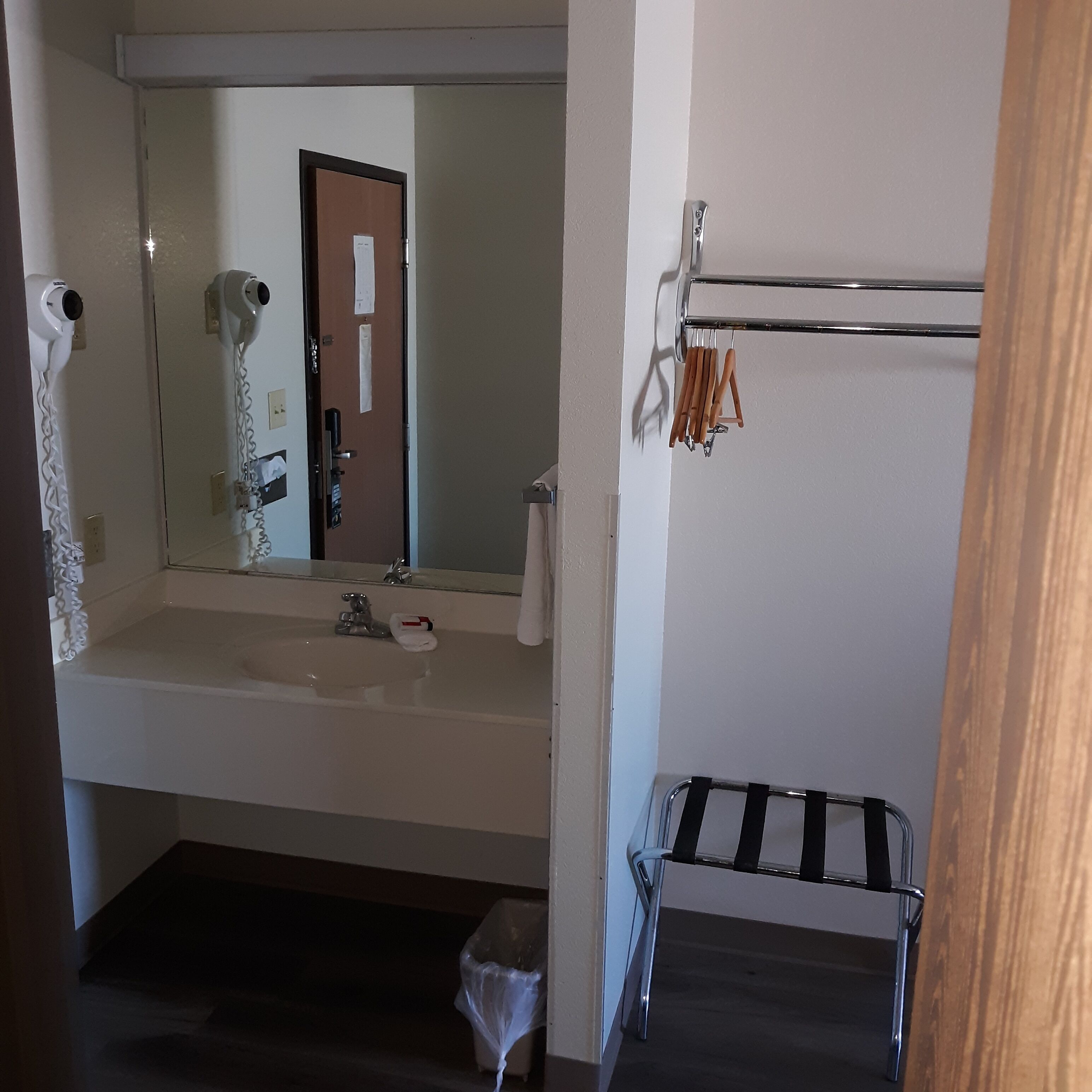 A bathroom with a sink, mirror, towel rack, and a small stool.