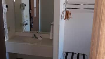 Un baño con lavamanos, espejo, toallero y un pequeño taburete.