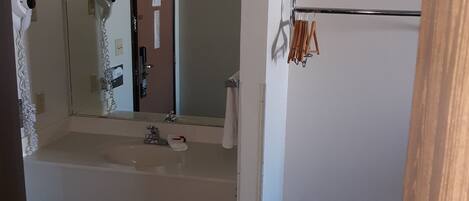 A bathroom with a sink, mirror, towel rack, and a small stool.