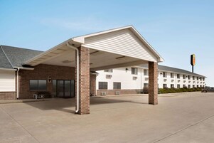 A motel with a covered parking area, brick facade, and a row of rooms.
