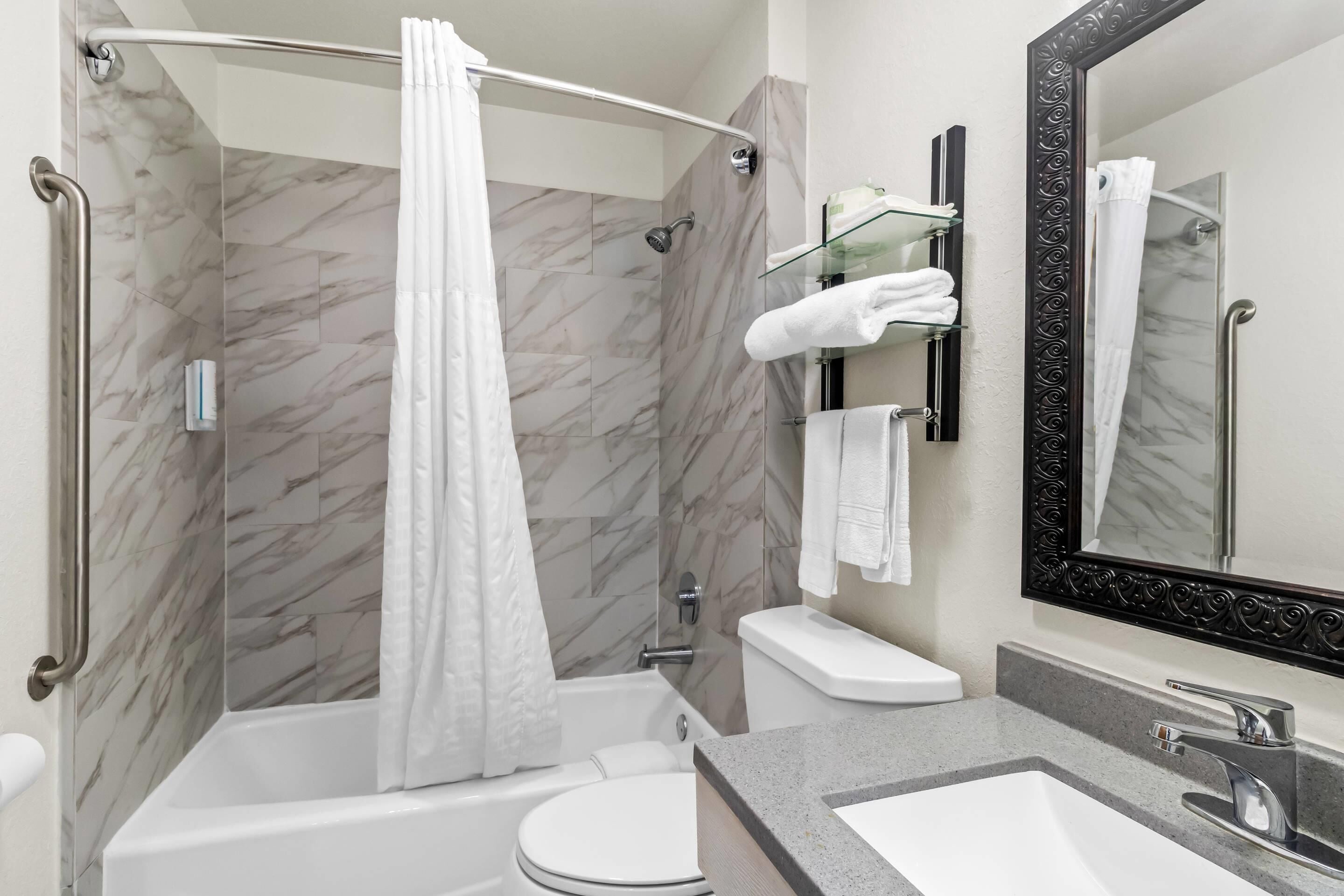 A modern bathroom with a shower, toilet, and sink.