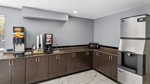 A modern kitchen with dark cabinets, a built-in microwave, a coffee machine, and a water dispenser. - Rodeway Inn Delmont (Delmont)