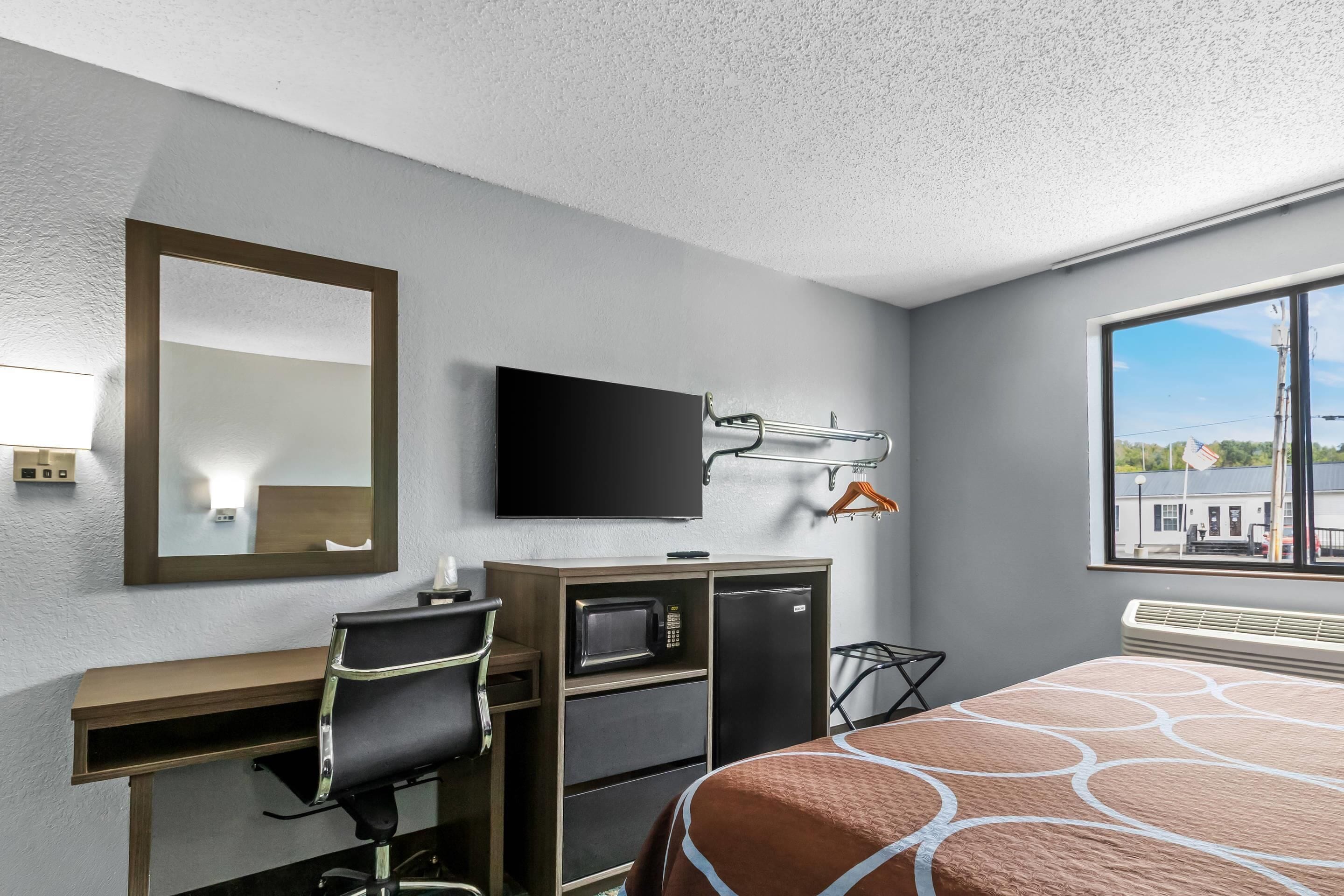 Une chambre d’hôtel équipée d’un lit, d’un bureau avec une chaise, d’une télévision, d’un four à micro-ondes et d’un radiateur.