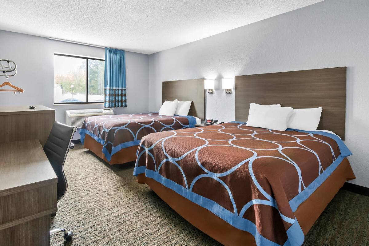 Una habitación de hotel con dos camas, un escritorio y una silla.