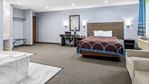 A hotel room with a bed, desk, chair, and a small table with a chair. - Rodeway Inn Delmont (Delmont)