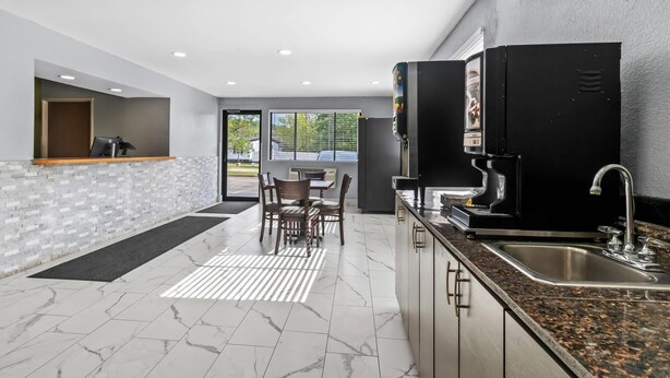 A modern kitchen with a granite countertop, stainless steel sink, and a coffee machine. - Rodeway Inn Delmont (Delmont)
