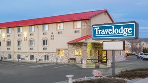 A Travelodge hotel with a red roof, stone facade, and a signboard. - Travelodge by Wyndham Loveland/Fort Collins Area (Loveland)