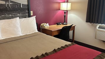Habitación de hotel con cama, escritorio con lámpara, teléfono y aire acondicionado instalado en la pared.
