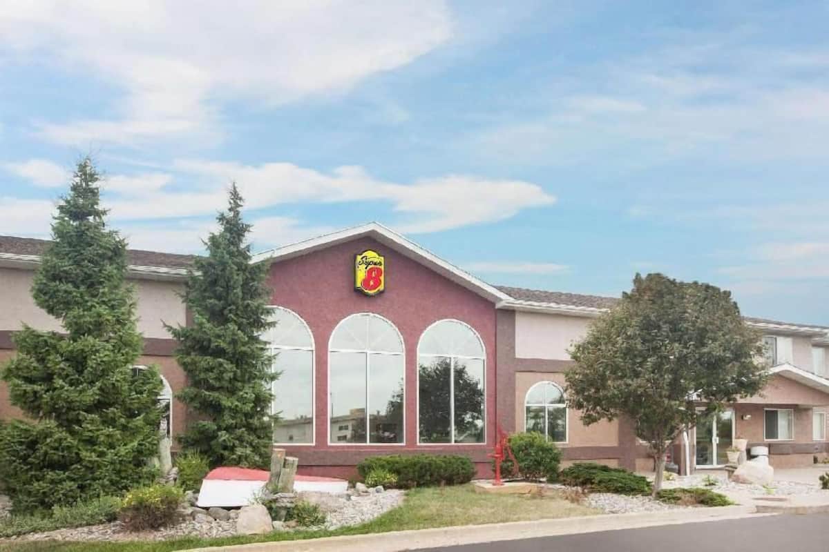 Un edificio con tetto rosso, un logo con uno stemma e ampie finestre ad arco.