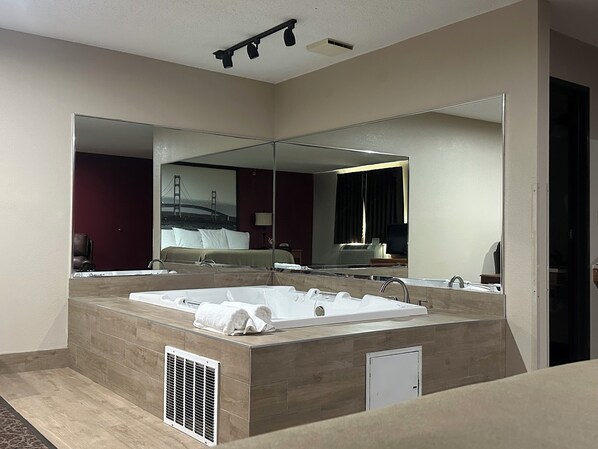 A modern hotel bathroom with a large bathtub, a walk-in shower, and a large mirror. - Super 8 by Wyndham West Branch (West Branch)