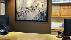 A reception desk with a framed welcome sign, a computer, a cash register, and a Super 8 sign.
