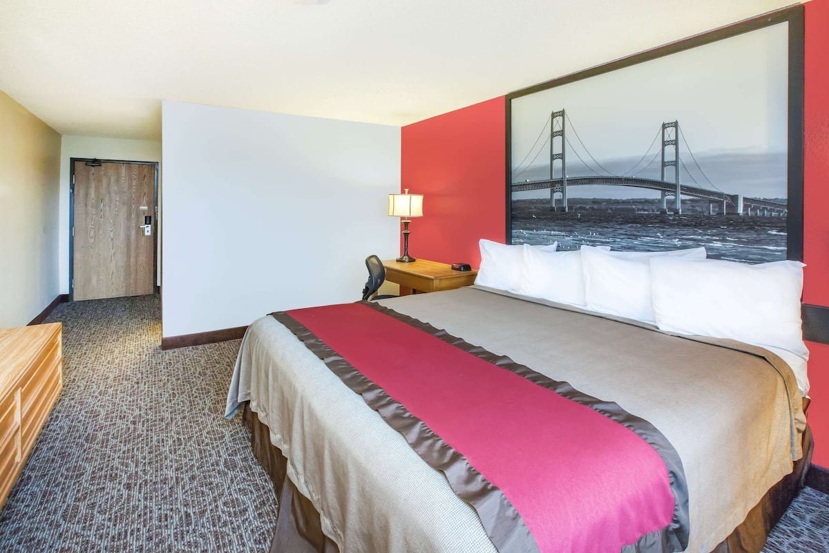 Una camera d'albergo con un letto grande, una scrivania, una sedia, una lampada e un'ampia finestra con vista su un ponte.