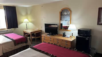 Habitación de hotel con dos camas, un escritorio, televisor, espejo, lámpara, cafetera y microondas.
