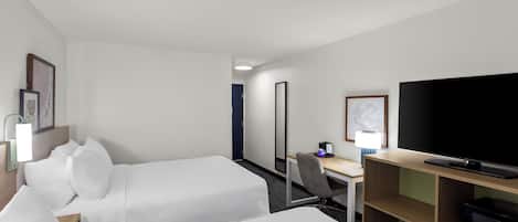 Una habitación de hotel con dos camas, un escritorio, una silla, un televisor y un espejo.