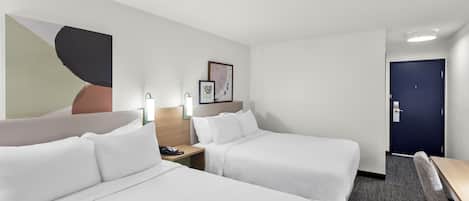 A hotel room with two beds, a desk, a chair, a nightstand, and a door.