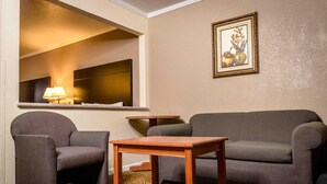 A living room with a grey sofa, two armchairs, a wooden coffee table, a small side table, a lamp, and a framed picture on the wall. - Executive Inn and Suites (Sacramento)