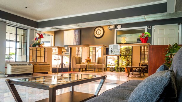 A modern lobby with a glass coffee table, seating area, and a reception desk. - Executive Inn and Suites (Sacramento)
