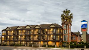 A hotel with multiple balconies, a palm tree, and a sign for Executive Inn & Suites. - Executive Inn and Suites (Sacramento)