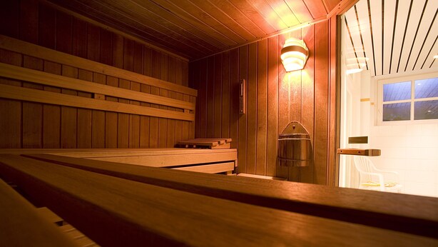Una sauna con bancos de madera y un accesorio de iluminación fijado a la pared.