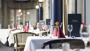 Un ambiente de restaurante con mesas dispuestas para comer, destacando manteles blancos, servilletas rojas y centros de mesa florales.