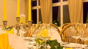 A dining table set with yellow candles, clear glassware, and a white tablecloth.