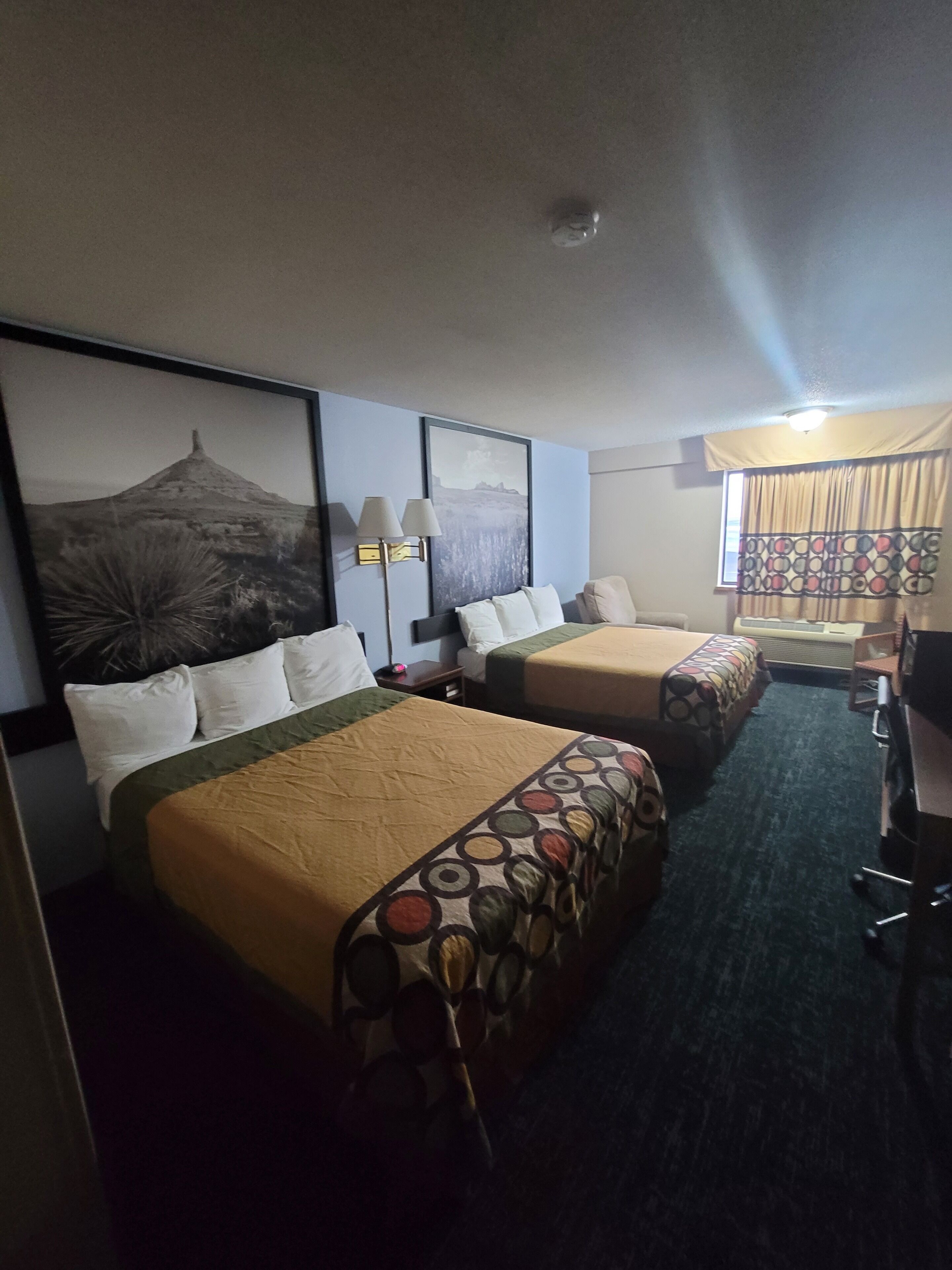A hotel room with two beds, a desk, and a chair.