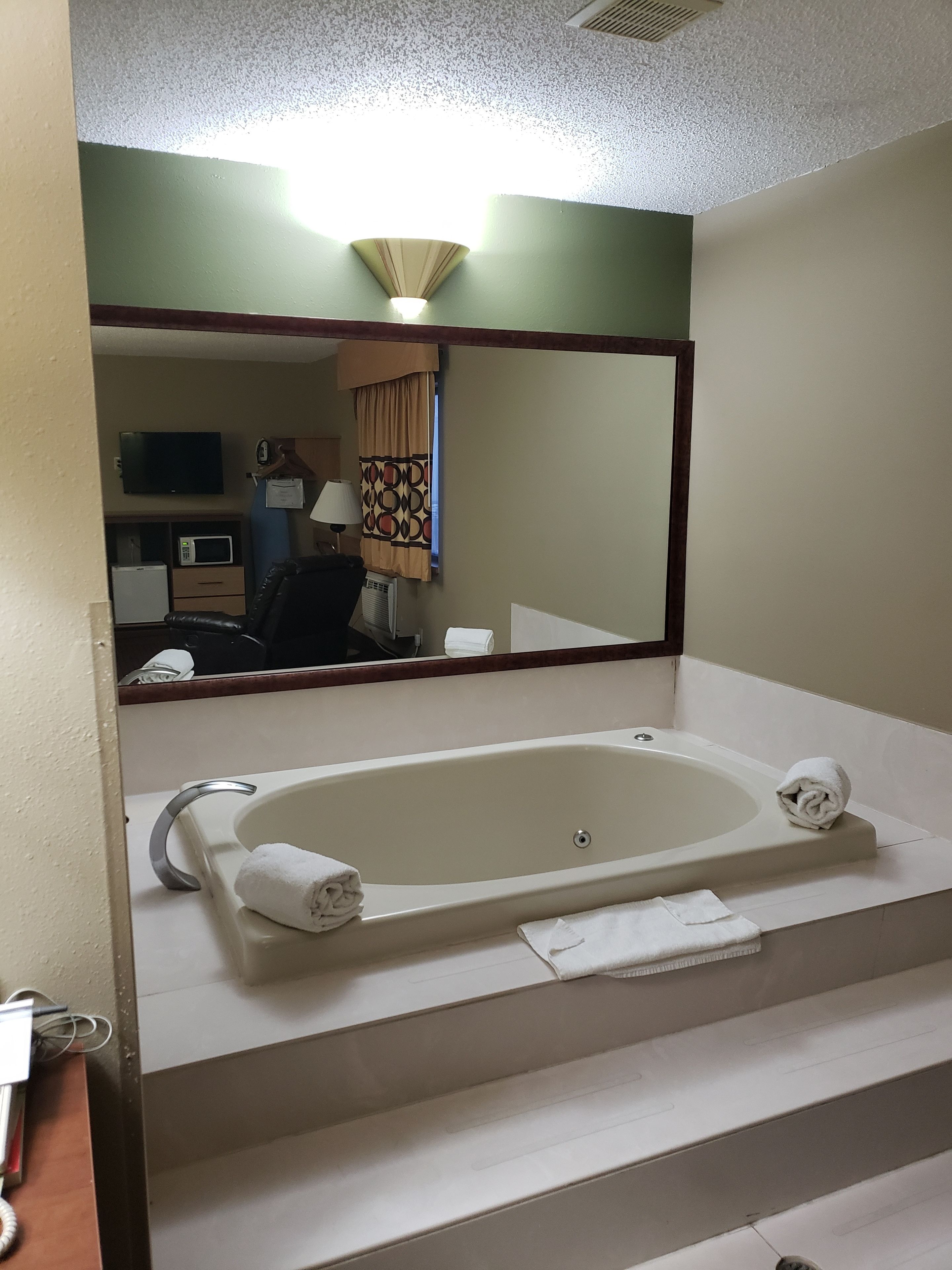 A bathroom with a bathtub, a mirror, a sink, and a toilet.