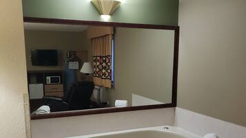 A bathroom with a bathtub, a mirror, a sink, and a toilet.