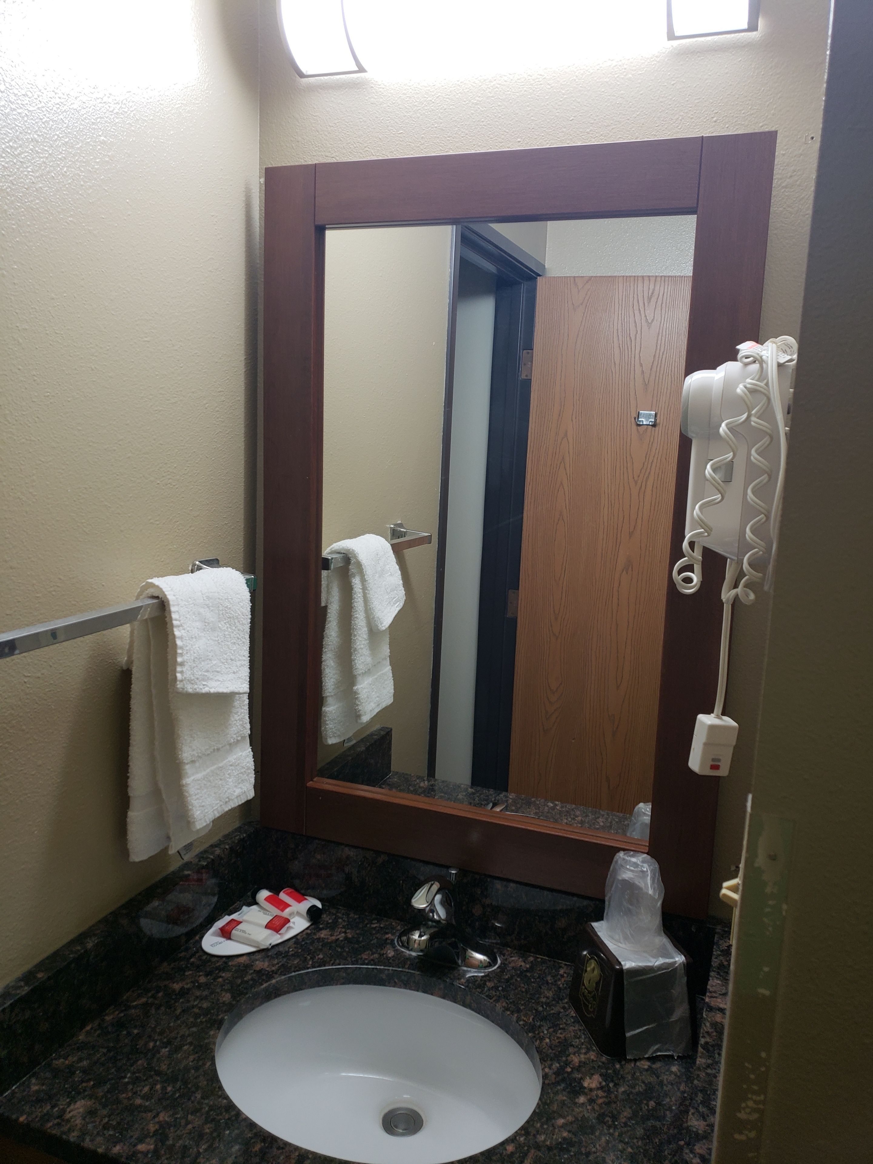 A bathroom with a white sink, a mirror, and a towel rack.