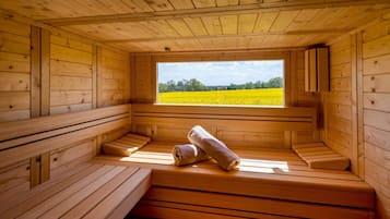 A wooden sauna with benches and a window offering a view of a yellow field.