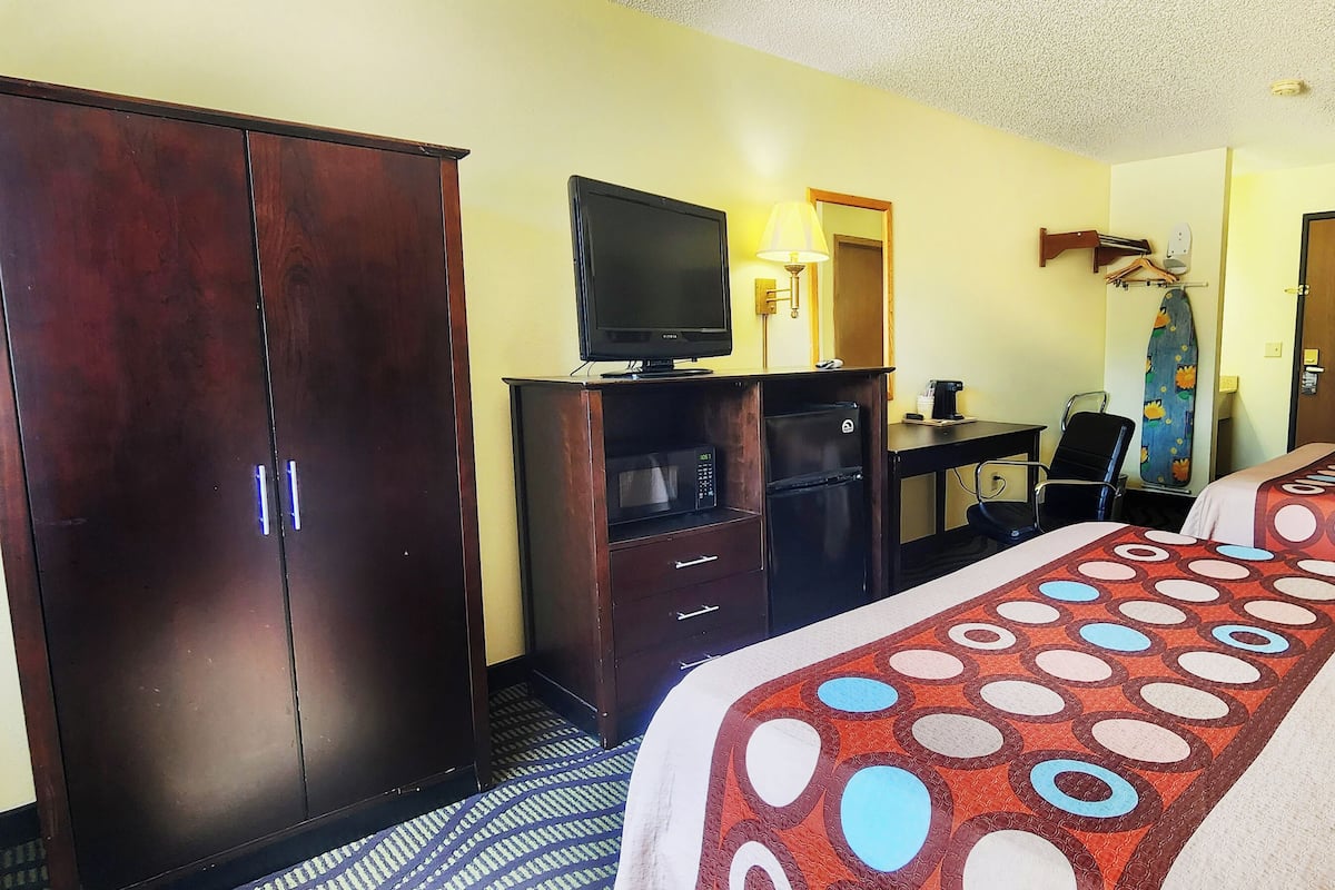 Hotelkamer met twee bedden, een televisie, een bureau met computer, een kledingkast en een douche.