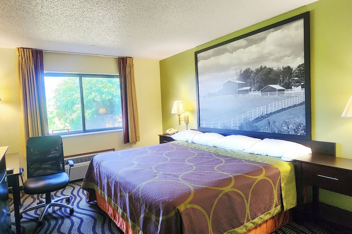 Een hotelkamer met een bed, bureau, stoel en een groot raam.
