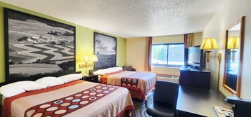 A hotel room with two beds, a desk, a chair, a TV, and a large painting on the wall.