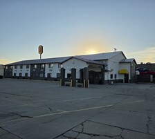 A building with a parking lot, a sign for a motel, and a clear sky.