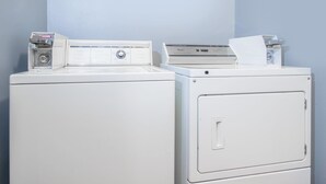 A laundry area with two white washing machines and a dryer.