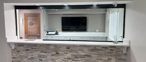Una cocina moderna con salpicadero de piedra, horno empotrado y un ventanal grande.