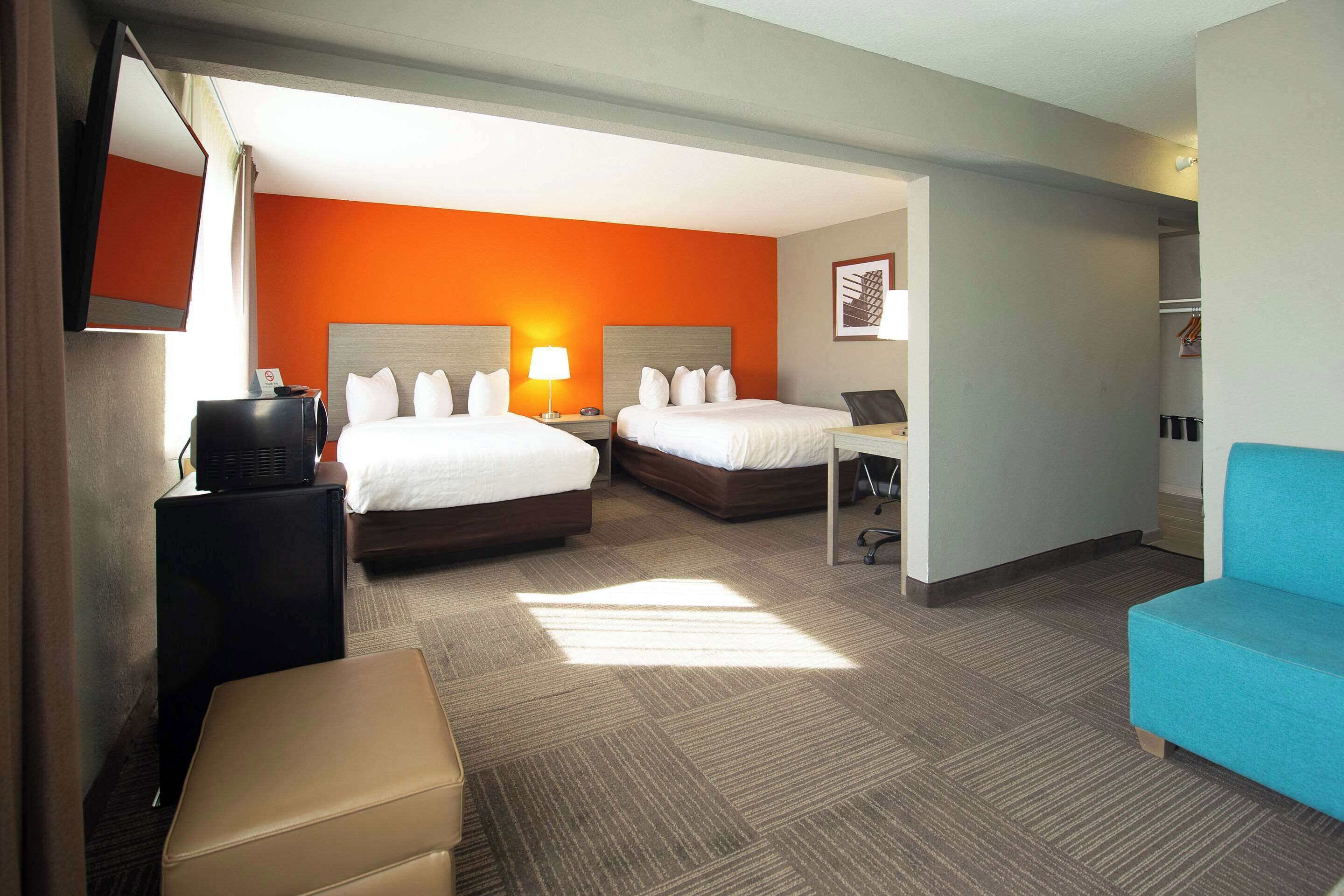 A hotel room with two beds, a desk, a chair, a TV, and a wardrobe.