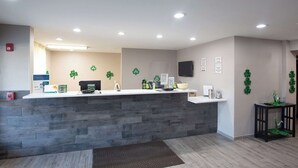 Un área de recepción con mostrador de piedra, televisor de pantalla plana y adornos de trébol verde.