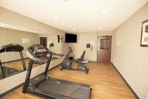 Un gimnasio de hotel con cinta de correr, elíptica y bicicleta estática.