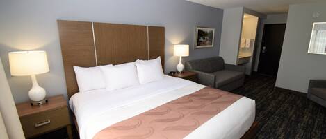 Une chambre d’hôtel avec un grand lit, deux tables de chevet avec des lampes, une chaise et un petit bureau.