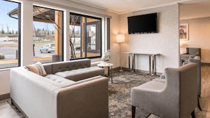Una habitación de hotel moderna con sofá, sillón y una mesita.
