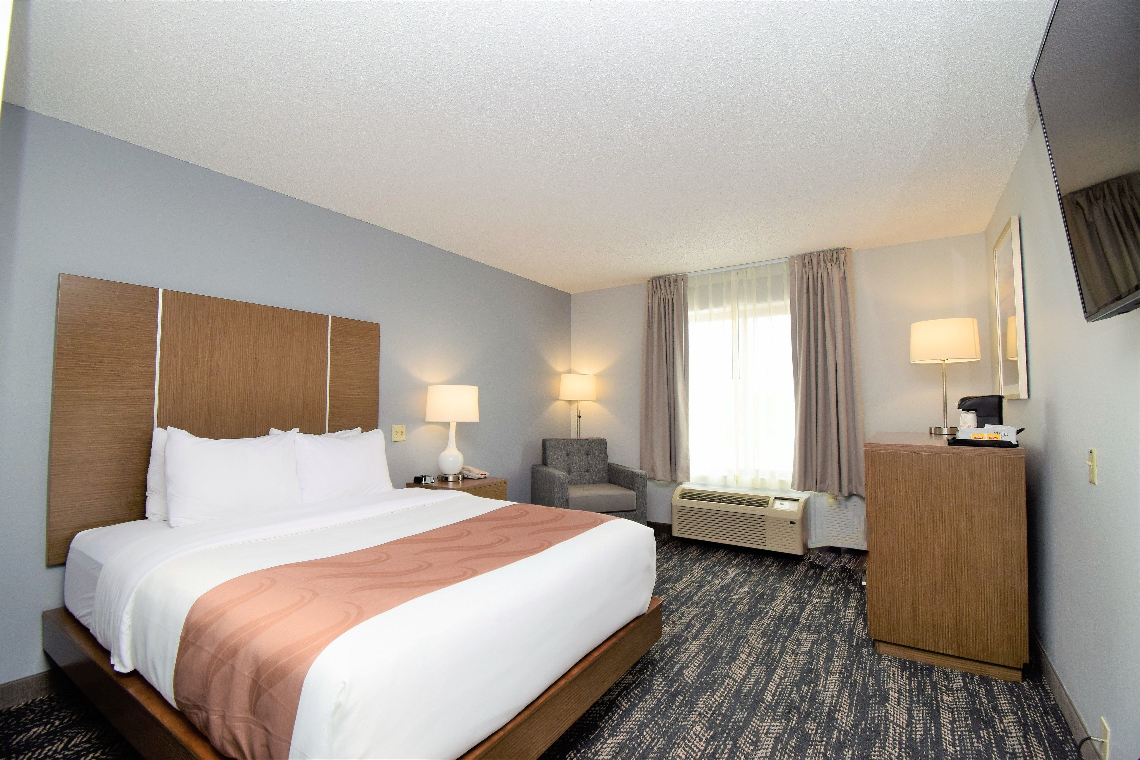 Ein Hotelzimmer mit einem großen Bett, einem Sessel, einem Schreibtisch und einem Spiegel.