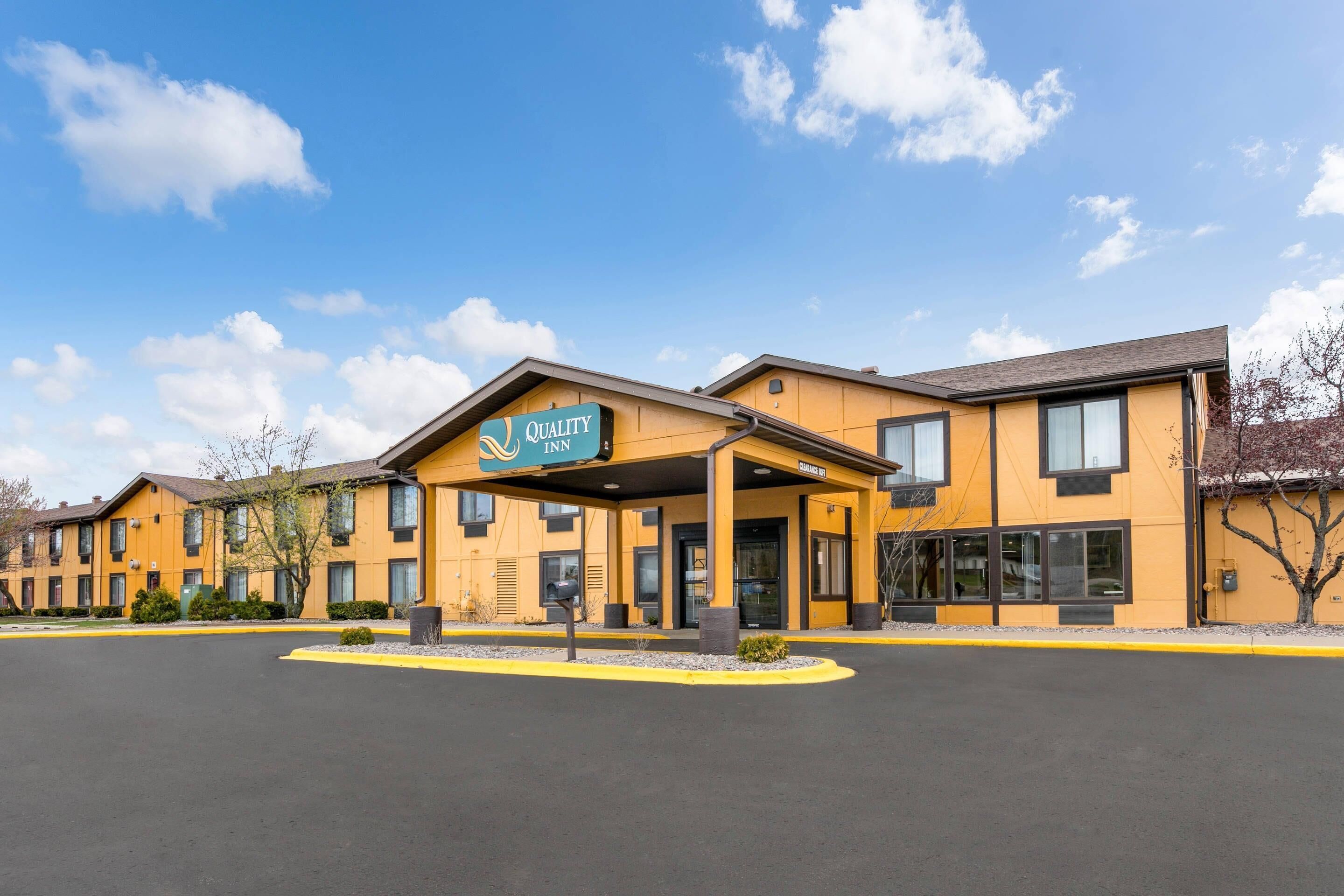 A Quality Inn hotel with a yellow facade, multiple windows, and a covered entrance.