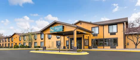 A Quality Inn hotel with a yellow facade, multiple windows, and a covered entrance.