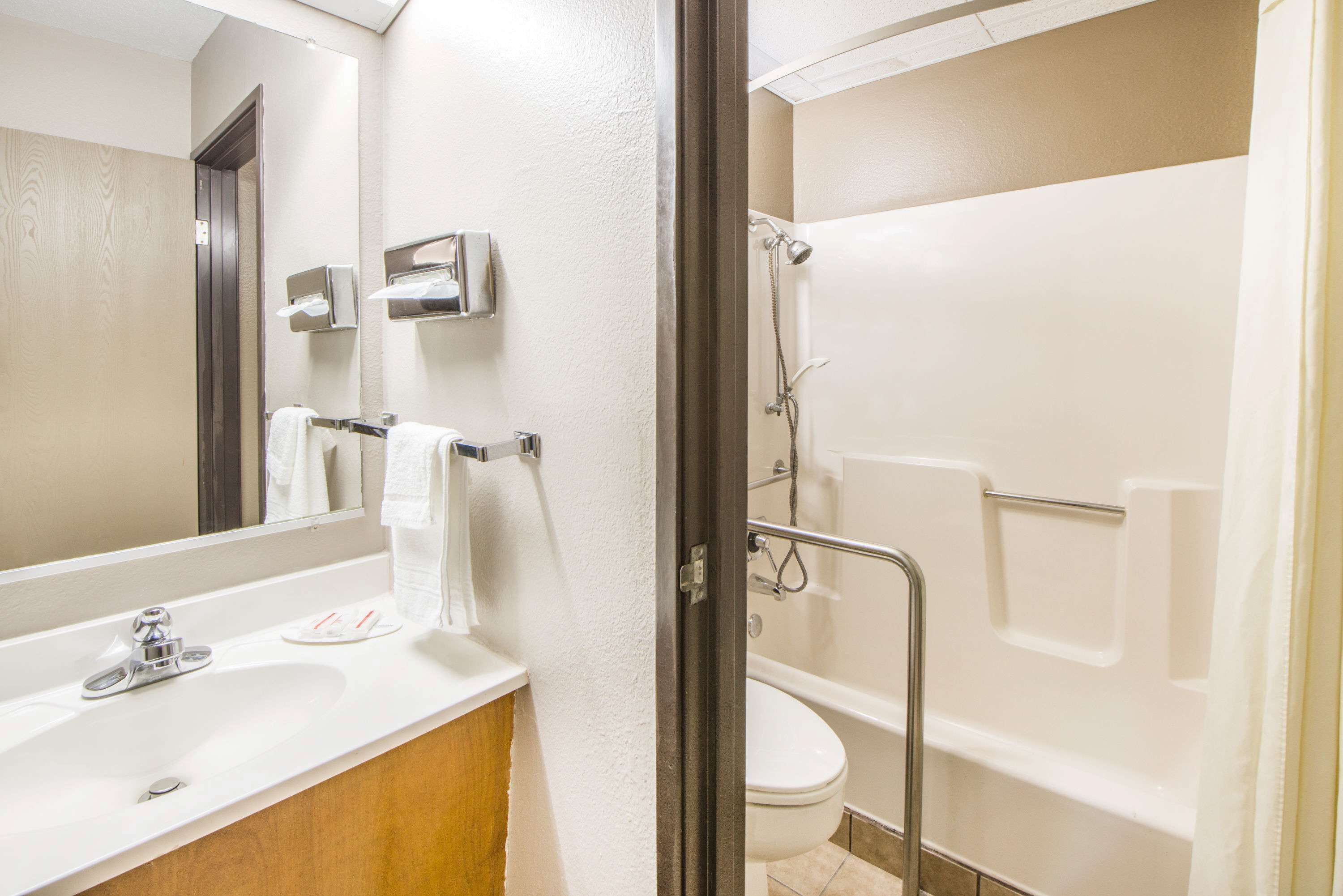 Een badkamer met een wastafel, spiegel, handdoekhouder, toilet en douche.