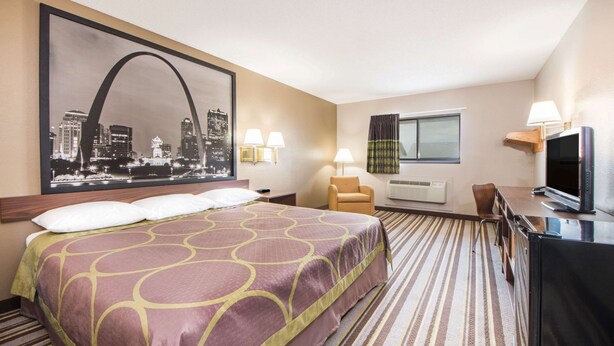 A hotel room with a large bed, a desk, a chair, a television, and a window with curtains. - Super 8 by Wyndham Nevada (Nevada)